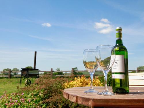 a bottle of wine and two wine glasses on a table at Bwthyn Onnen-Oa5 in Ystrad Meurig