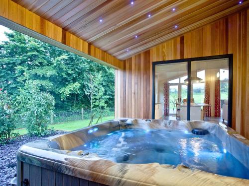 a large hot tub in a room with a large window at Willow Lodge in Hassocks