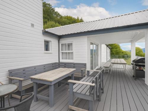 a wooden deck with tables and chairs and a grill at Chapelburn in Lawers