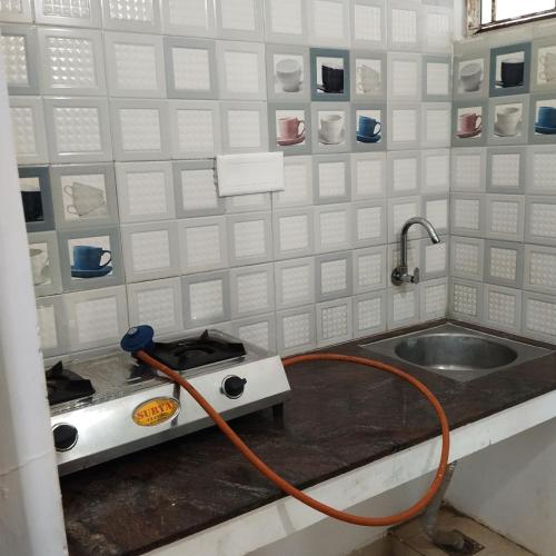 a kitchen with a sink and a hose at Sifa Guest House in Chennai