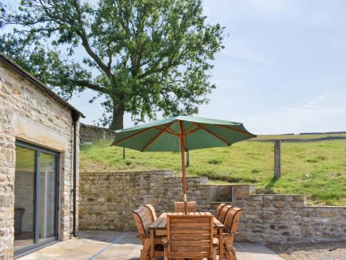 a wooden table with an umbrella on a patio at Deer Park - Uk33360 in Reeth