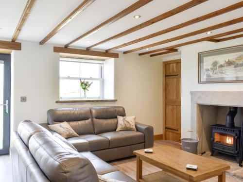 a living room with a leather couch and a fireplace at Deer Park - Uk33360 in Reeth