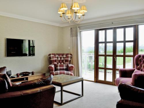 a living room with a couch and chairs and a chandelier at Lochnagar Lodge in Aviemore