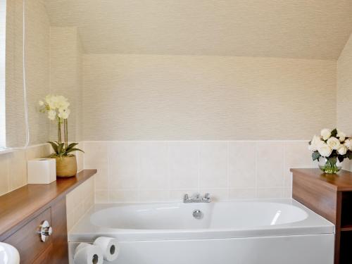 a bathroom with a bath tub with a vase of flowers at Lochnagar Lodge in Aviemore