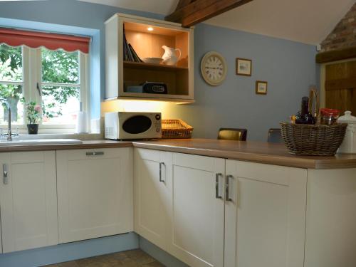 a kitchen with white cabinets and a counter with a microwave at Rose Cottage in Rillington