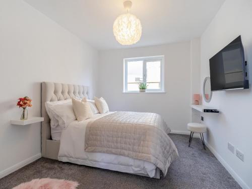 a white bedroom with a bed and a flat screen tv at The Old School House in Barnsley