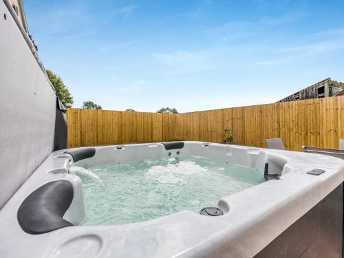 a hot tub in a backyard with a fence at The Old Stables in Cumberworth