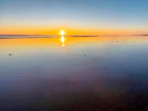 a sunset on a beach with the sun reflecting in the water at The Pastures - Uk41853 in Maltby le Marsh