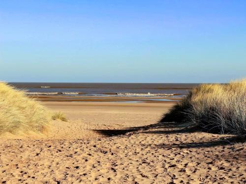 a sandy beach with grass and the ocean at The Pastures - Uk41853 in Maltby le Marsh