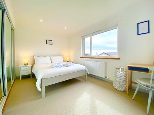 a white bedroom with a bed and a window at Seagrass in Lamlash
