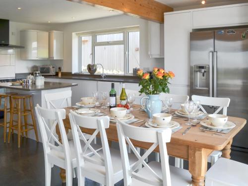 a kitchen with a wooden table and white chairs at Roskear in Crackington Haven