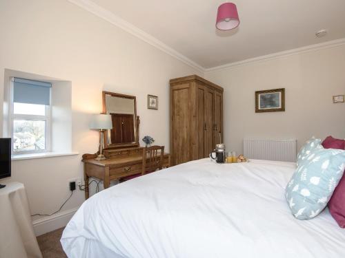 a bedroom with a white bed and a dresser and a mirror at The Laburnums in Askham