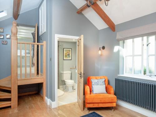 an orange chair in a room with a toilet at Wheelwright Cottages in Branscombe