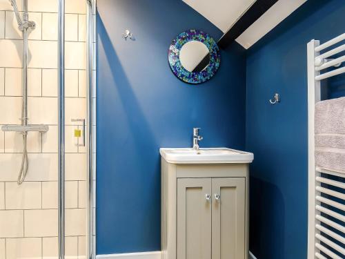 a blue bathroom with a sink and a shower at Ty Afon in Talybont