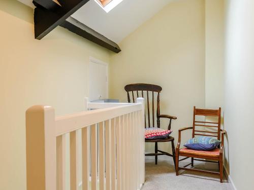 a room with two chairs and a white staircase at Ty Afon in Talybont