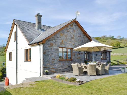 a cottage with a table and chairs and an umbrella at Maes Y Bryn Farmhouse in Llanwrda
