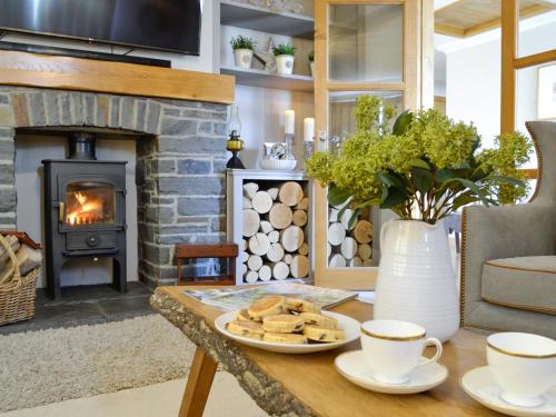 a table with two cups of coffee and a fireplace at Maes Y Bryn Farmhouse in Llanwrda