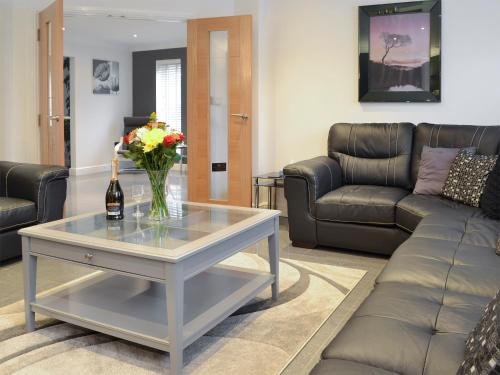 a living room with a couch and a table with flowers at Oswald House in Llansantffraid