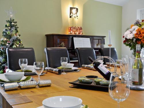 a table with wine glasses and a christmas tree at Oswald House in Llansantffraid