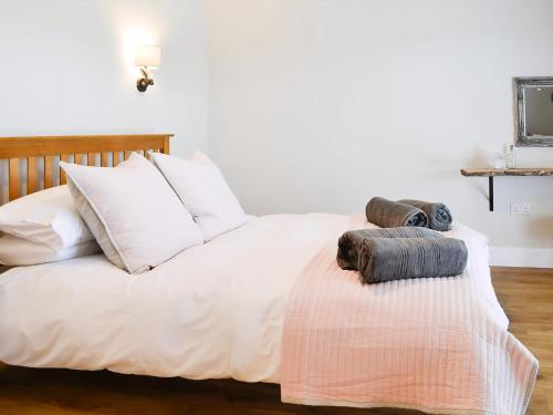 a white bed with pillows and towels on it at The Byre in Castle Douglas