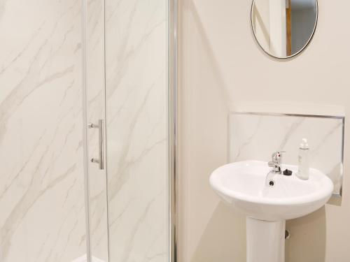 a white bathroom with a sink and a shower at The Byre in Castle Douglas