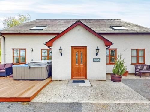 a small white house with a wooden door at Willow Cottage-Uk2788 in Penmaen-mawr