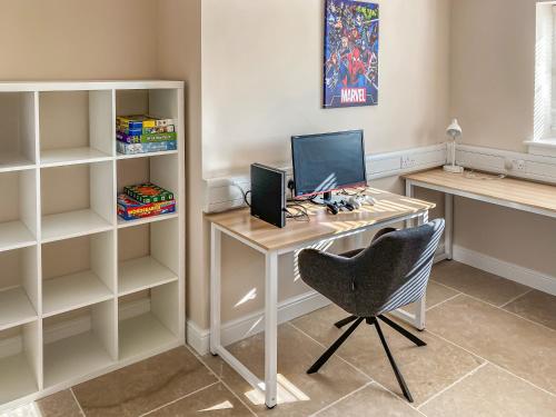 a desk with a computer and a chair in a room at Barnyard in Chetnole