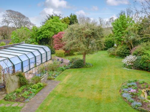 a garden with a greenhouse and some plants at Carnethic House - One Acre View in Fowey