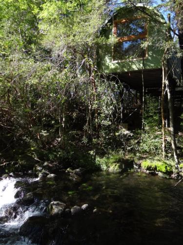 a cabin in the woods next to a stream at Huincaterra in Villarrica