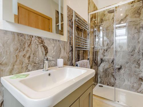 a bathroom with a sink and a shower at Penshenkin Barn in Llanfihangel-nant-Melan