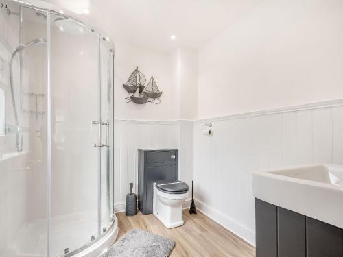 a bathroom with a shower and a toilet and a sink at Pennyard House in Banwell