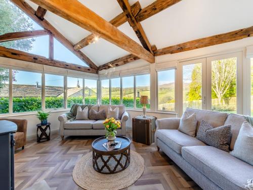 a living room with couches and windows at Badger Hill Barn in Malham