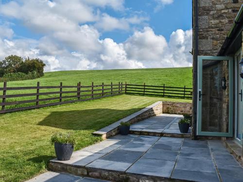 a house with a porch with a fence and a field at Swiss Cottage in Lancaster