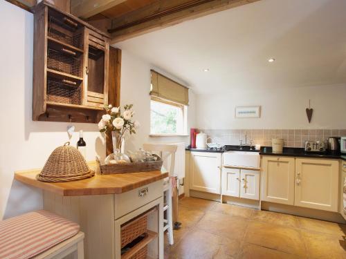 a kitchen with white cabinets and a vase of flowers at The Barn in Burley