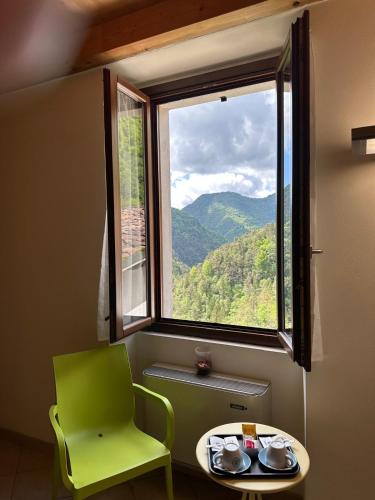 a table and a green chair in front of a window at Locanda Graziella in Moerna