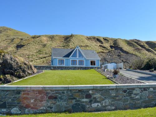 a blue house on top of a stone wall at Seal Rocks in Lendalfoot