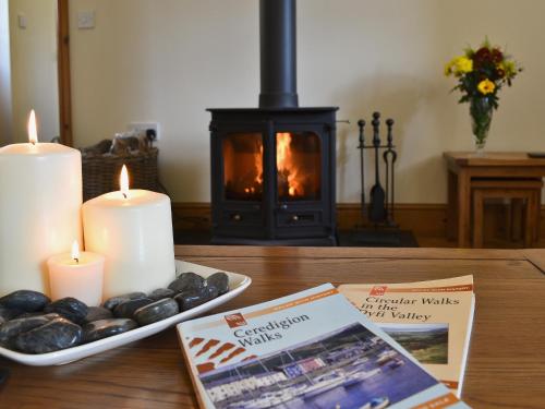 a table with candles and a plate of rocks and a fireplace at Eithinog in Talybont