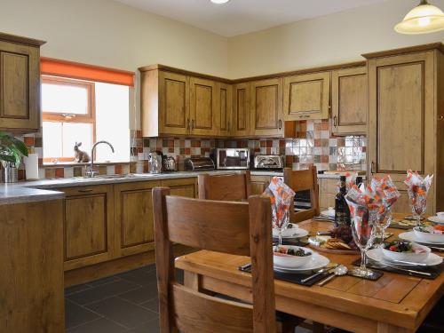a kitchen with wooden cabinets and a wooden table with food at Eithinog in Talybont