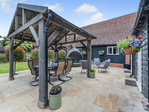 a wooden pergola with a table and chairs on a patio at The Barn - Uk49371 in Send