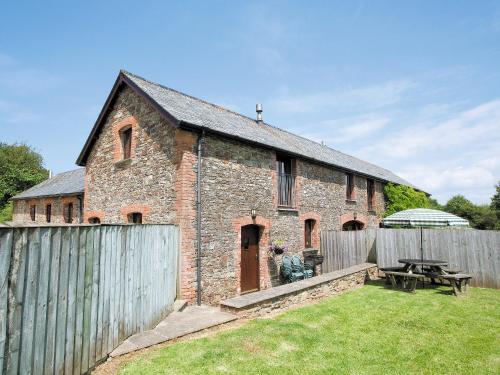 an old brick building with a fence and a picnic table at Swallows Cottage in Parkham