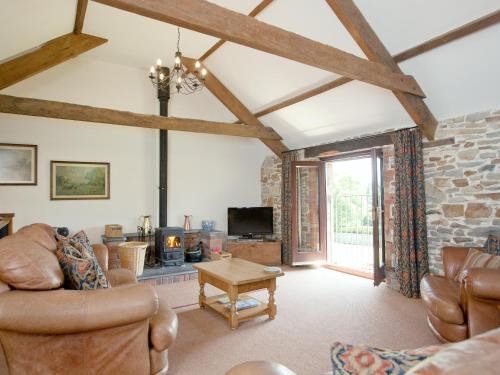 a living room with leather furniture and a stone wall at Swallows Cottage in Parkham
