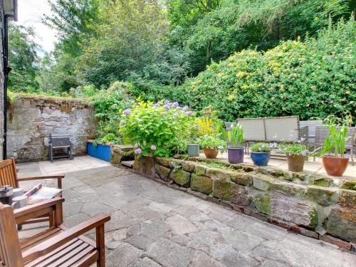 a garden with potted plants on a stone wall at Heron House in Tweedmouth