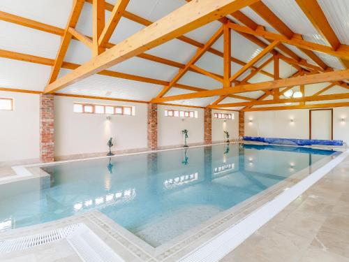 a swimming pool in a building with wooden beams at Granary Barn - Ukc5405 in Banham