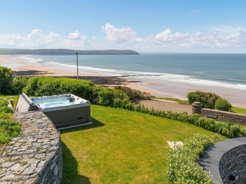 a hot tub sitting on top of a hill next to a beach at Cyan in Mortehoe