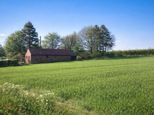 a field of grass with a barn in the background at The Barn in Cantley