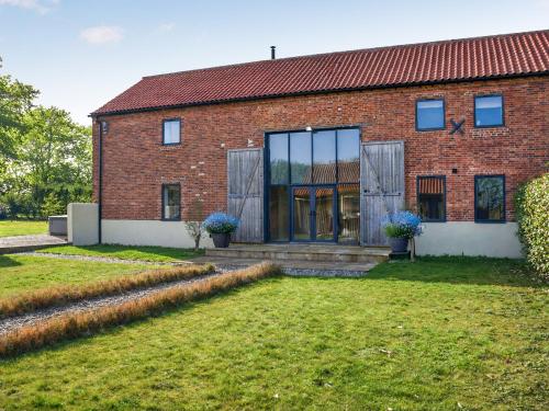 a red brick house with a large glass window at South Barn in Heydon