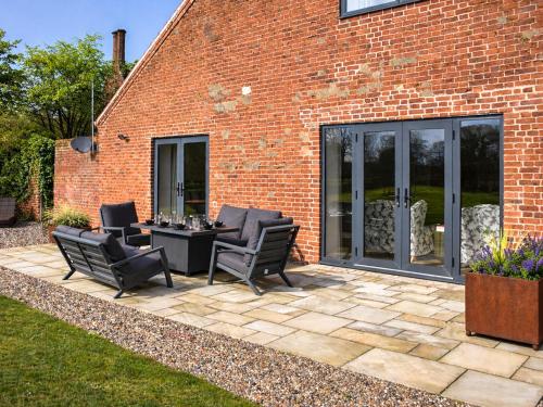 a patio with chairs and a table in front of a brick building at South Barn in Heydon