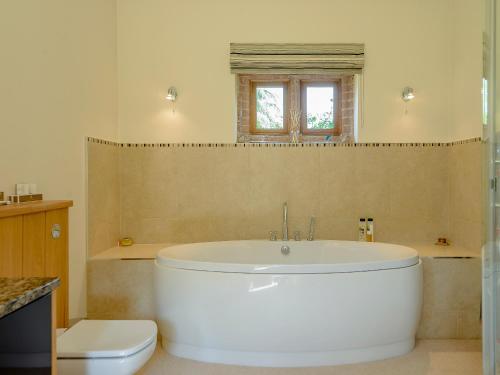 a bathroom with a white tub and a toilet at Courtyard Lodge in Edwinstowe