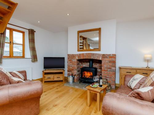 a living room with a fireplace and a tv at The Old Laundry - Uk12136 in Hewelsfield