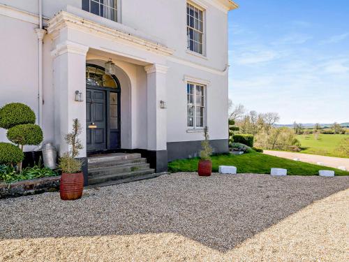a white house with a black door and some plants at Pengethley Manor - Uk39045 in Peterstow
